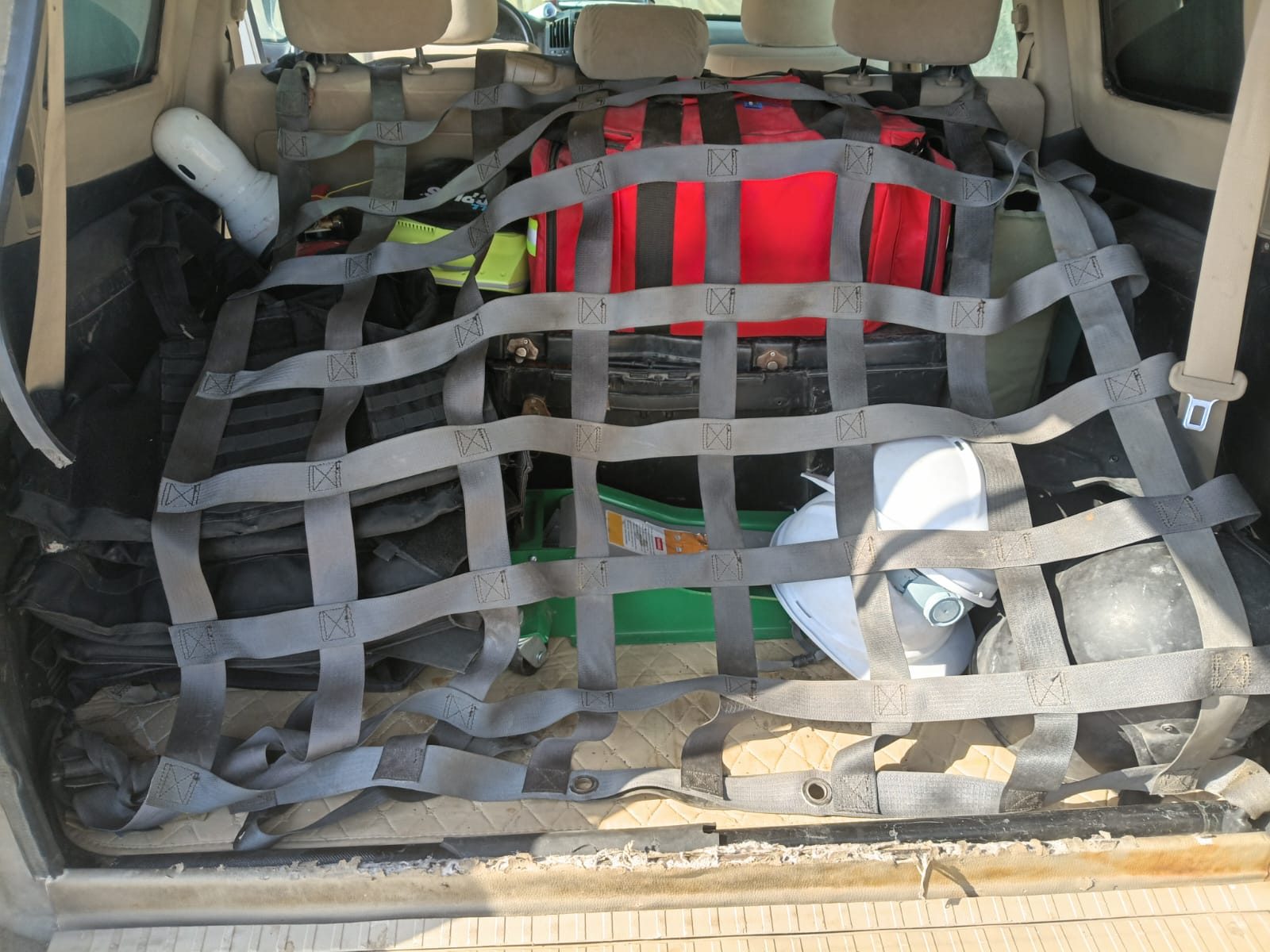 Medical and recovery kit secured under a cargo net in the vehicle