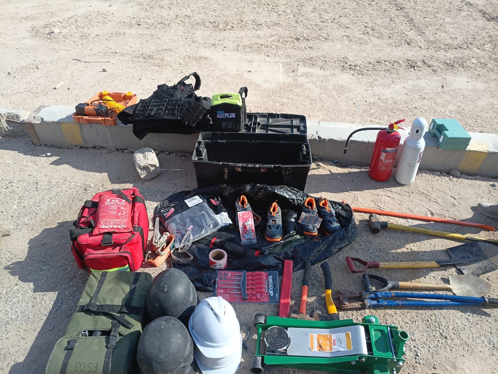 Protection-vehicle kit laid out for inspection: helmets, trauma bags, extinguishers and jack