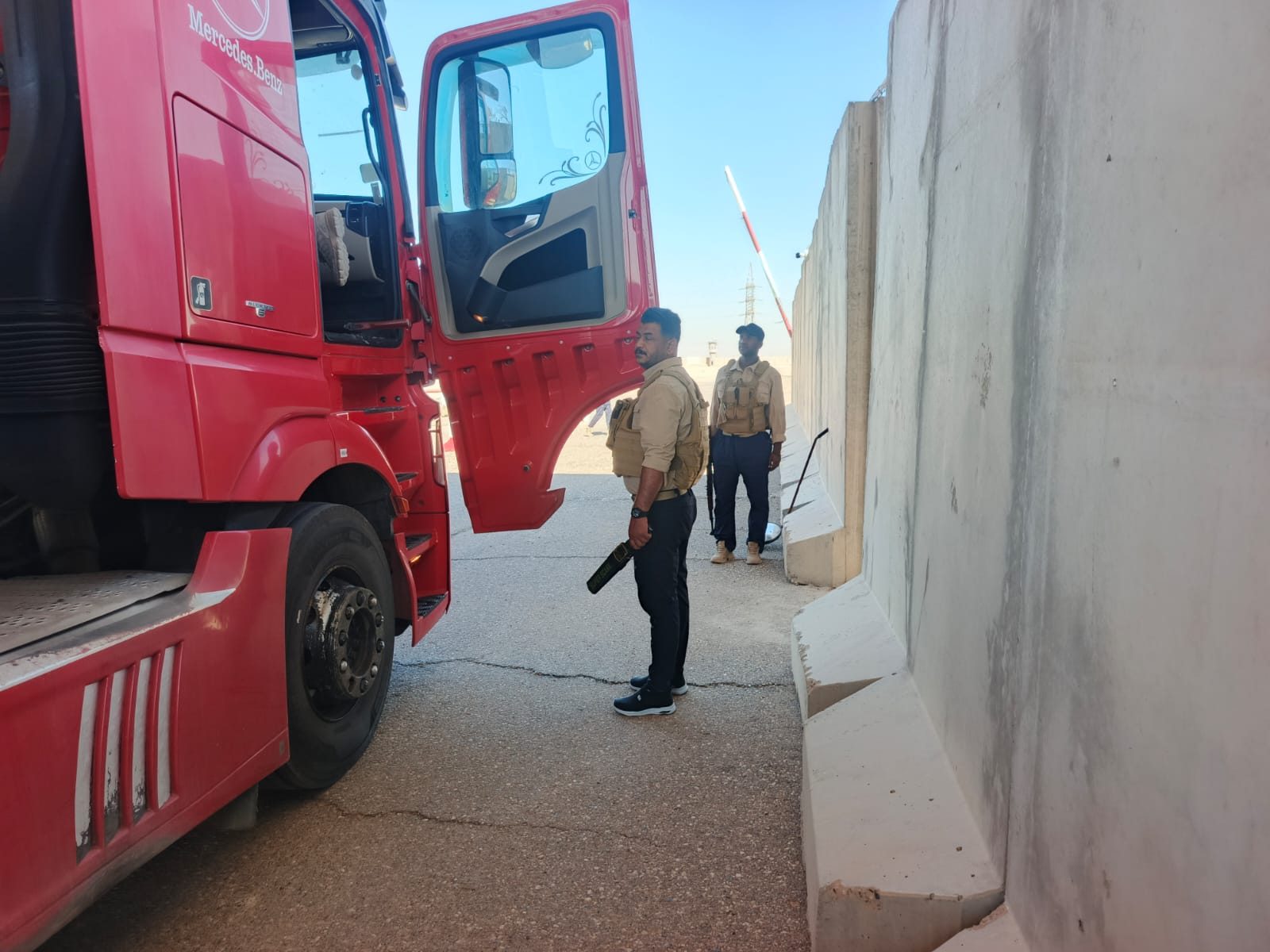 Diri Al-Nassir guard searching a truck with a metal detector at a vehicle entry control point