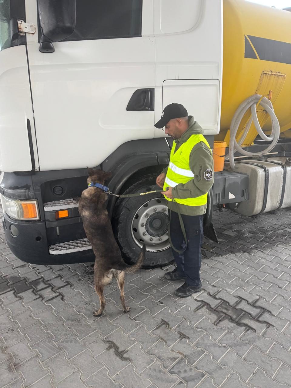 A handler and detection dog search a tanker’s wheels