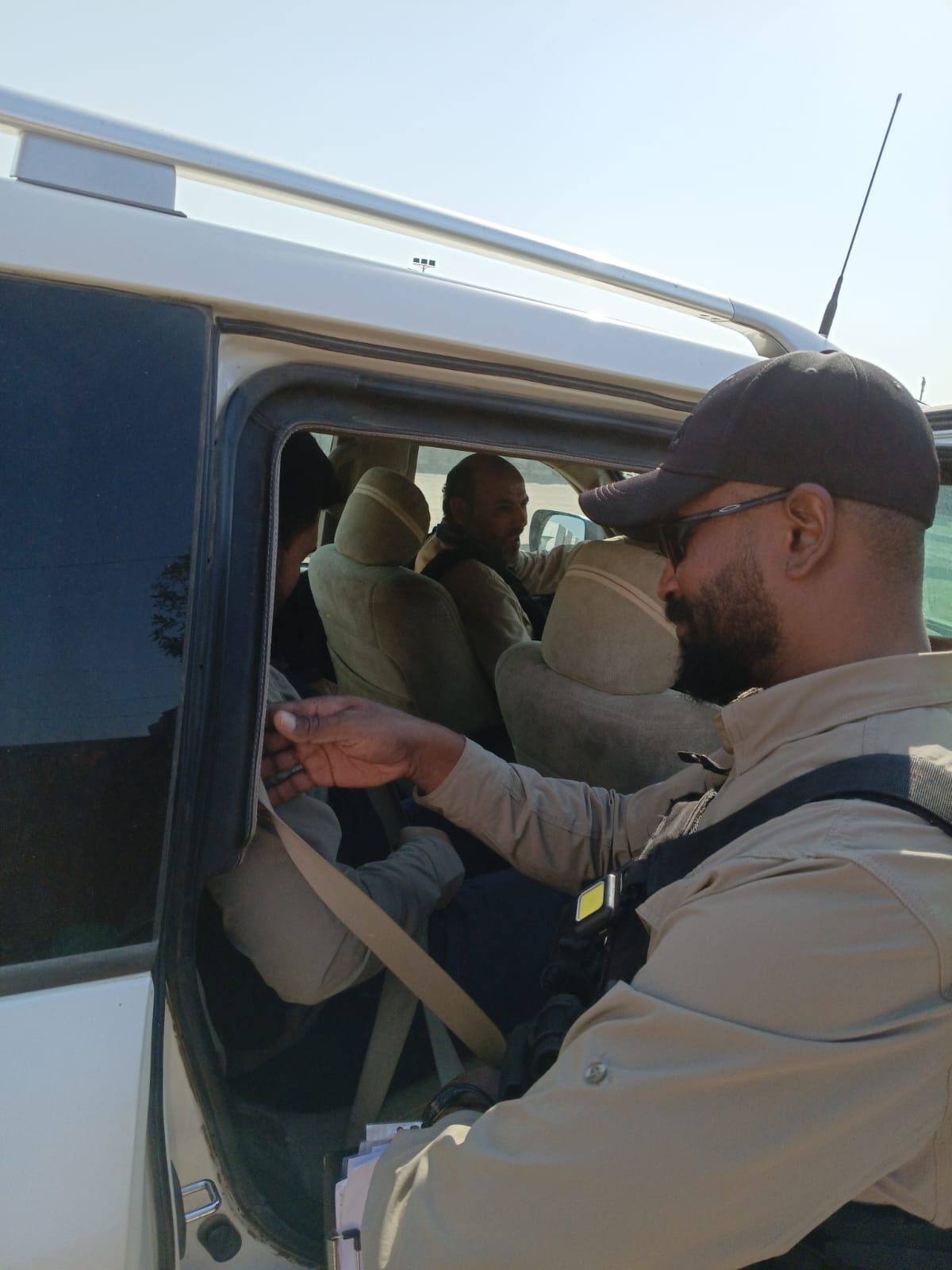 A protective-detail member checks passengers’ seatbelts before a move