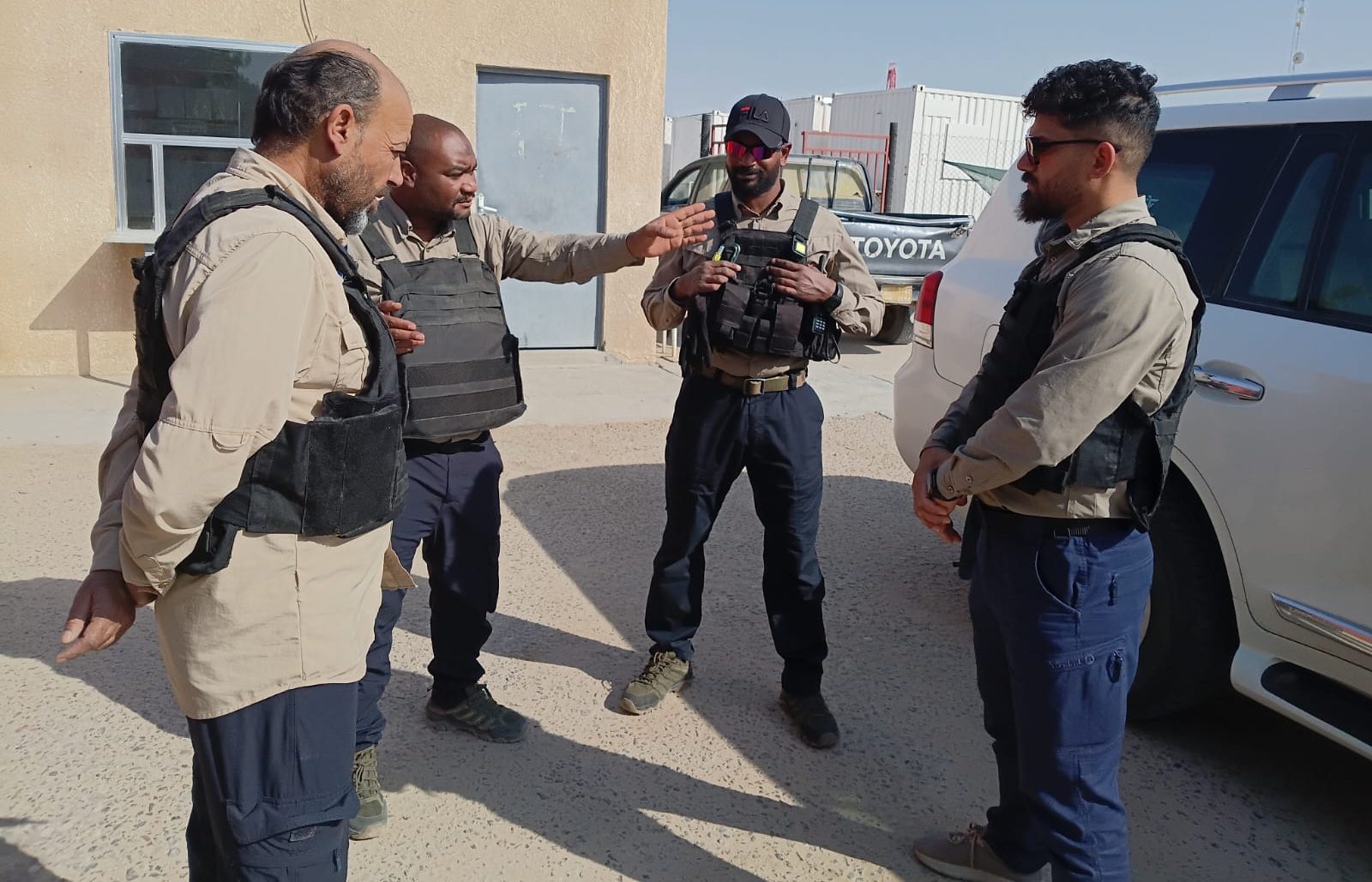 Protective team briefing beside the vehicle before a mission
