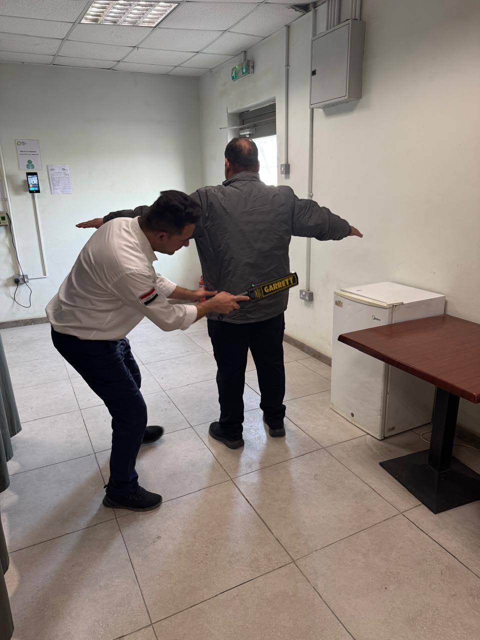 حارس يفتّش زائراً في غرفة التفتيش